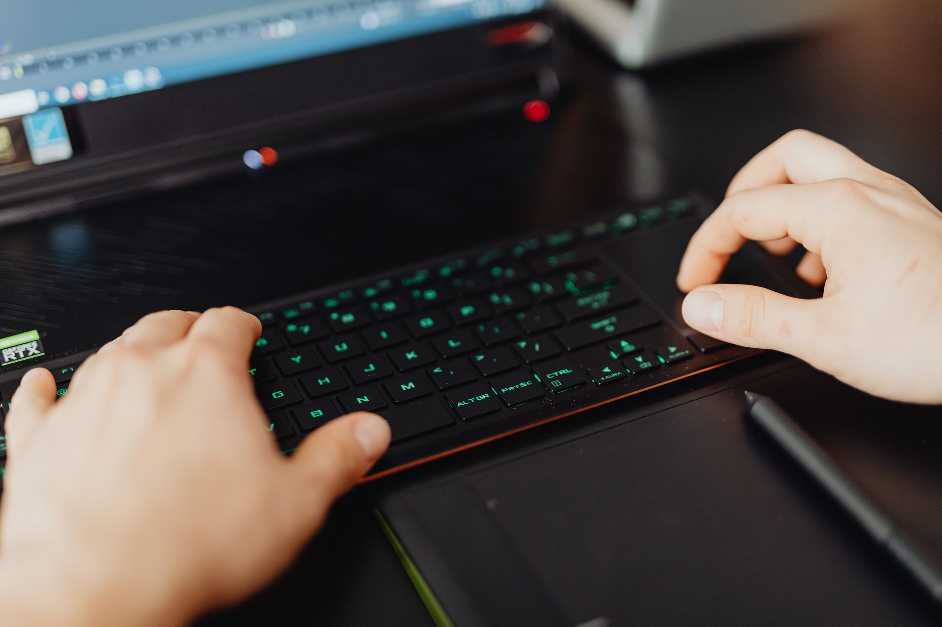 Close-up of hands typing on an RGB keyboard in a modern office