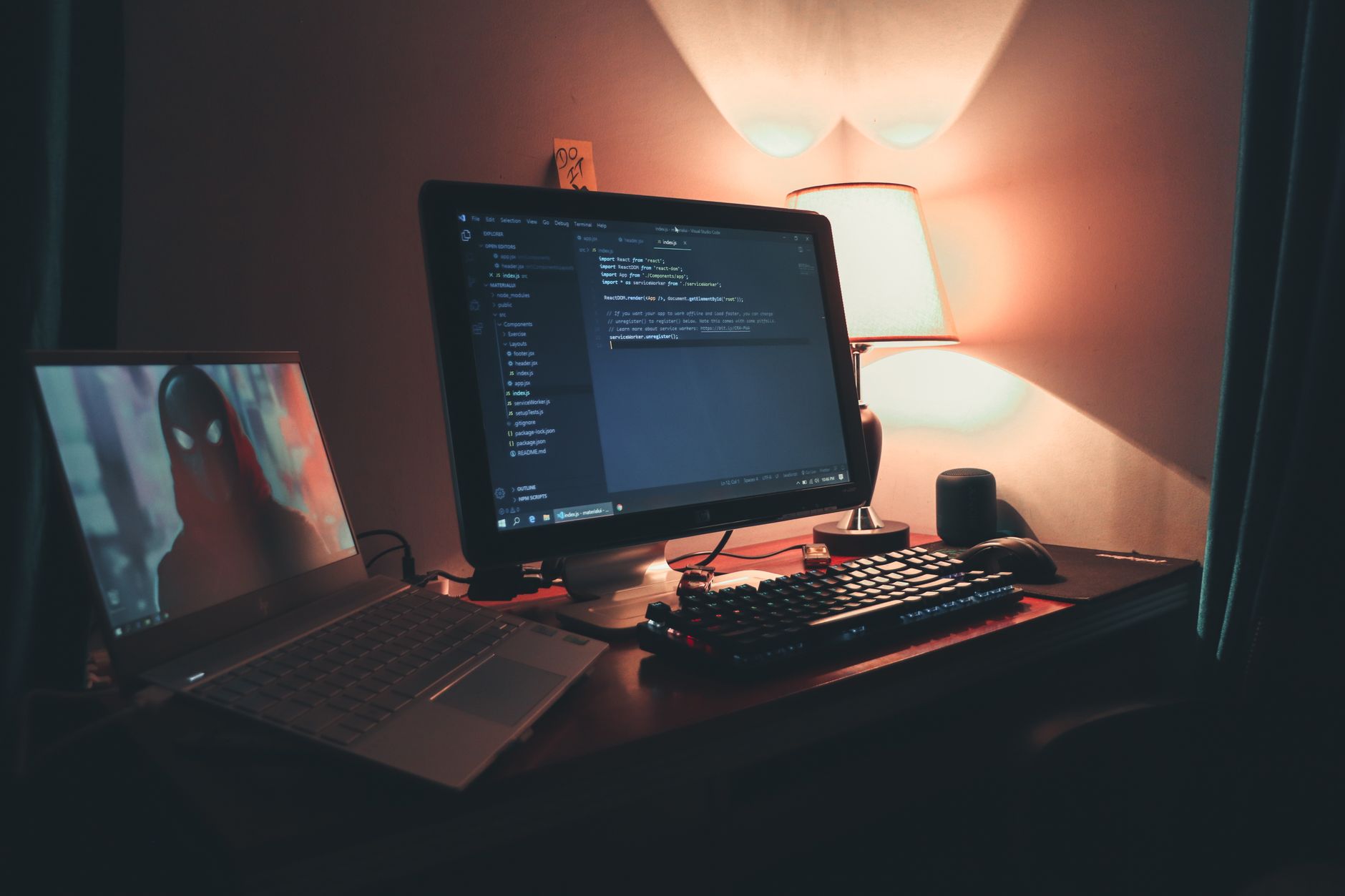 Warmly lit home office with two screens showing code