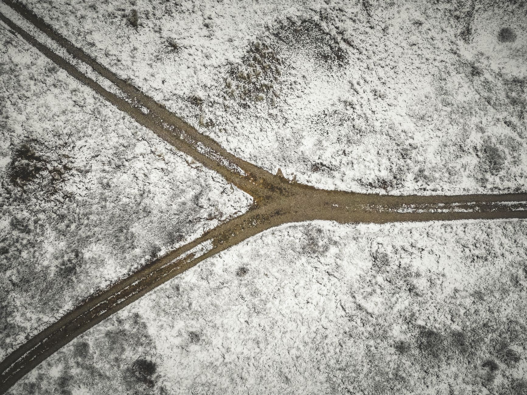 A dirt road forking into two paths in a snowy landscape, symbolizing branching