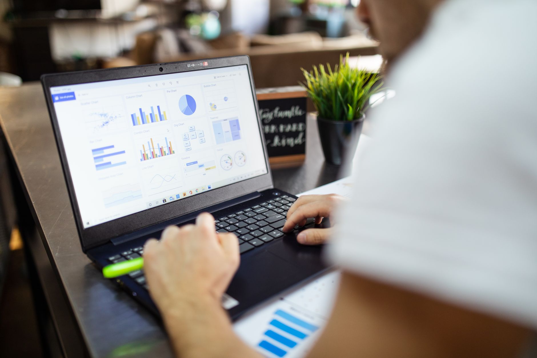Person reviewing business charts and graphs on a laptop in an office